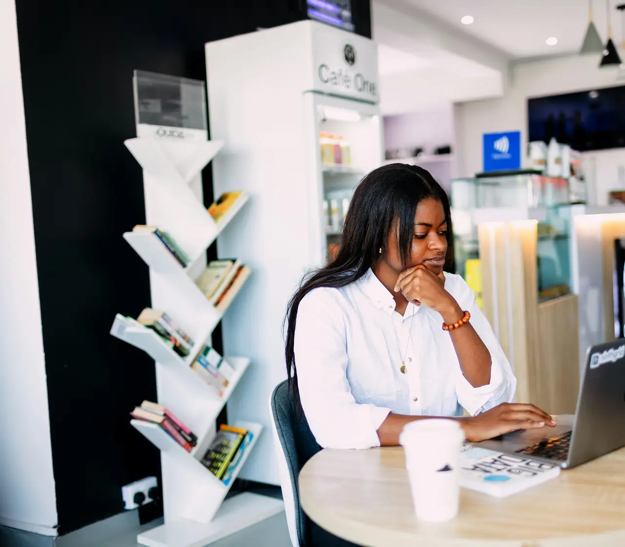 An accounting professional working on a laptop at a café table in Lagos